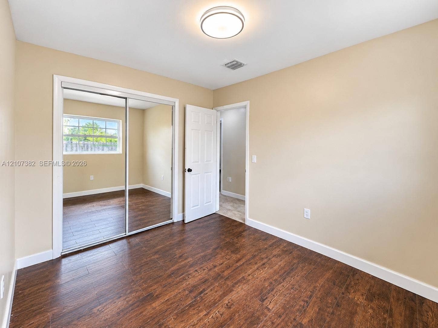 859 Caroline Circle, Palm Beach, FL 33413 Interior room featuring wood-finish flooring, sliding mirror-panel closet doors, a multi-panel interior door, and a circular flush-mount ceiling light fixture