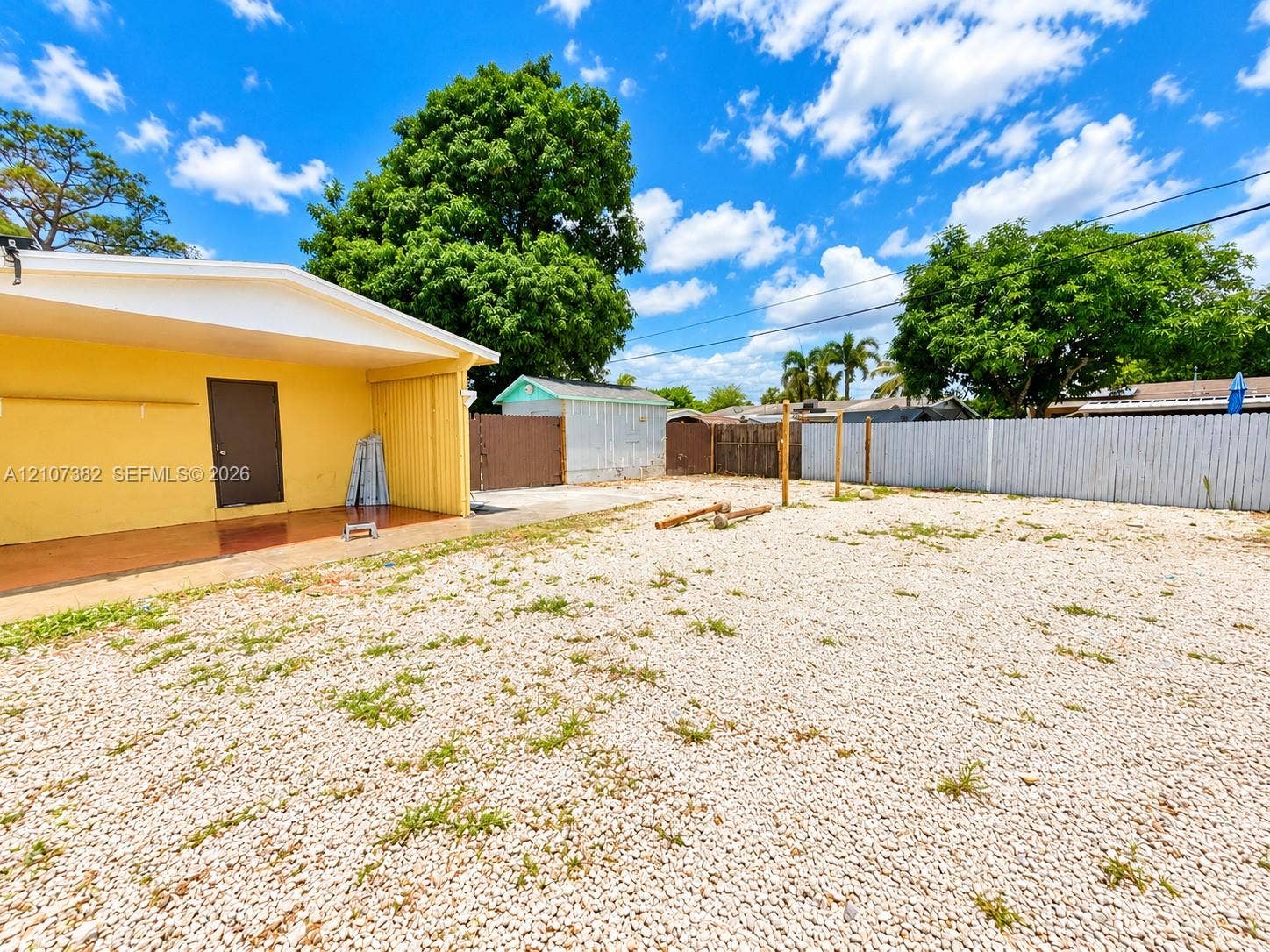 859 Caroline Circle, Palm Beach, FL 33413 Exterior area featuring a covered patio, gravel ground cover, detached storage shed, and perimeter fencing