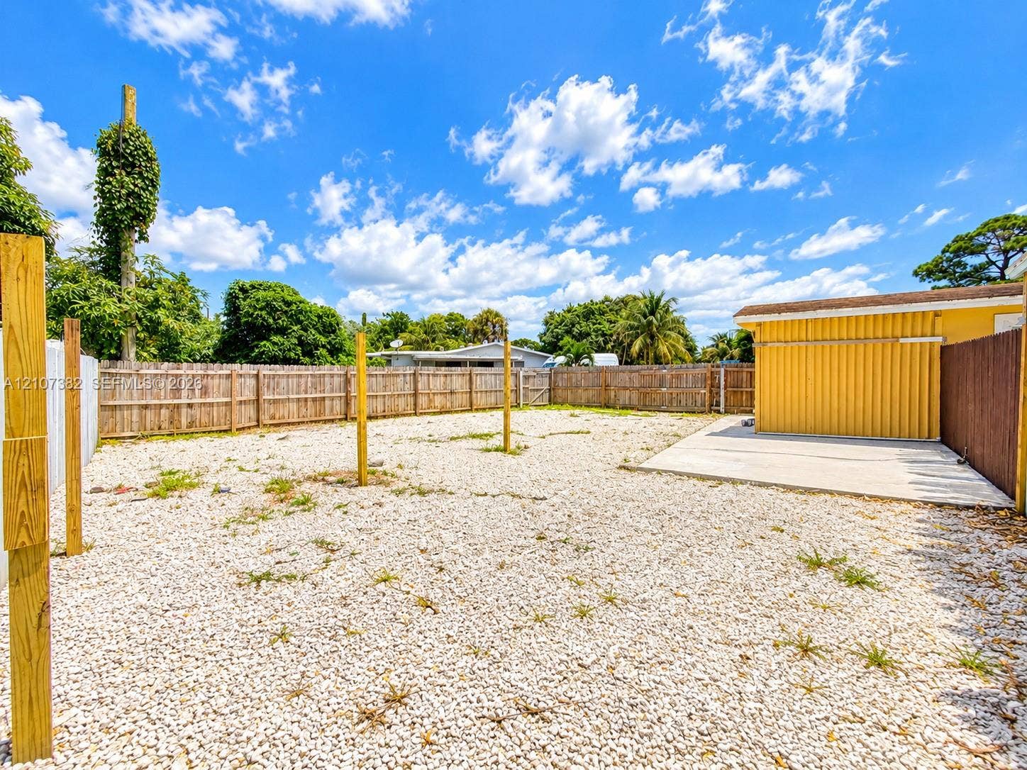 859 Caroline Circle, Palm Beach, FL 33413 Fenced backyard featuring a gravel surface, concrete patio, and vertical wood structural posts