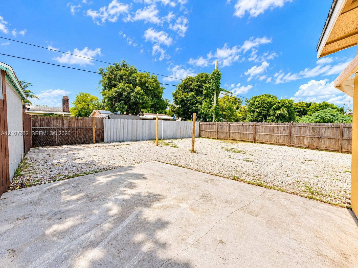 859 Caroline Circle, Palm Beach, FL 33413 Backyard featuring a concrete patio, gravel ground cover, and full wood perimeter fencing