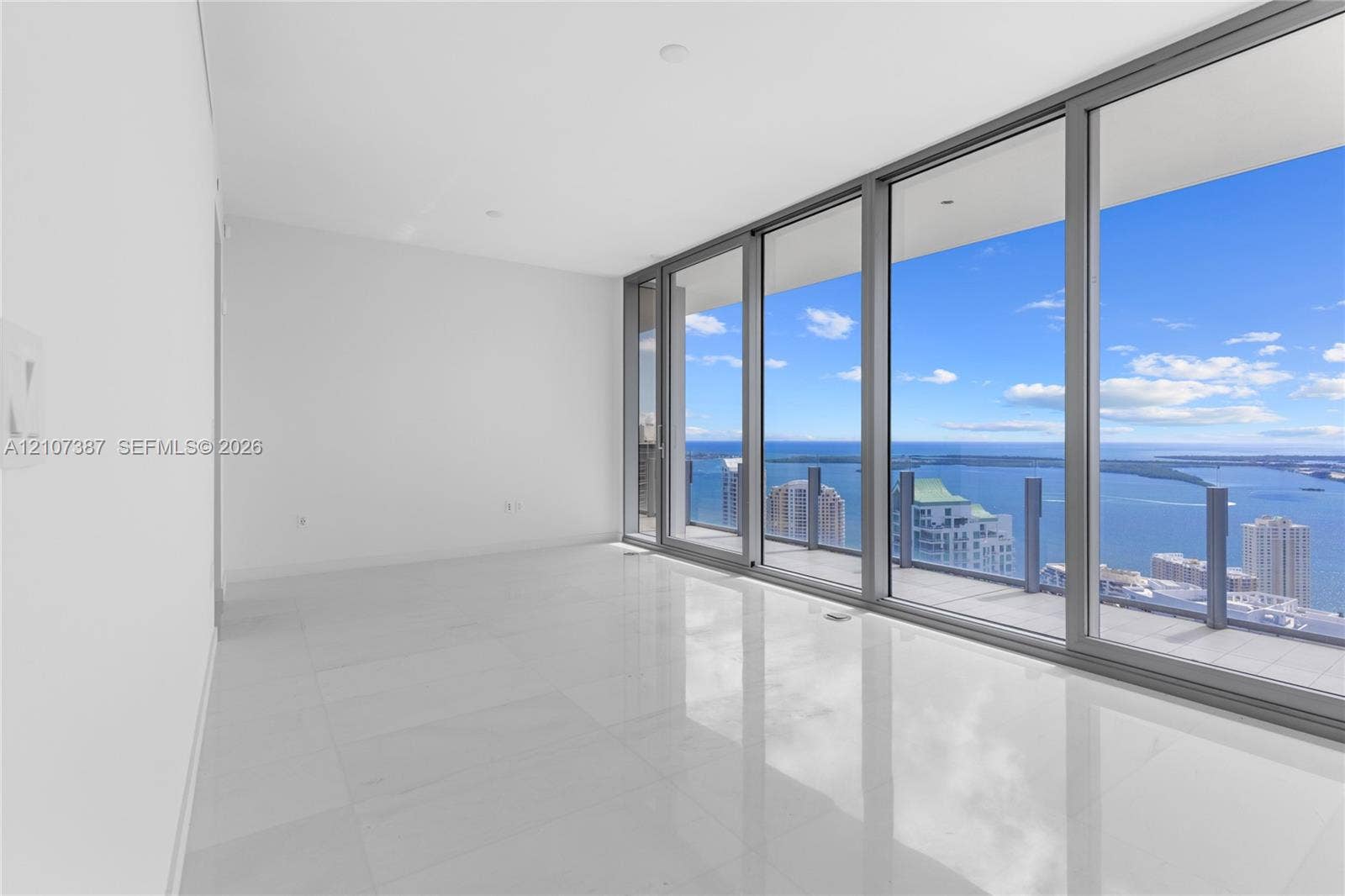 Floor-to-ceiling glass wall, polished tile flooring, recessed ceiling lighting, and expansive balcony with glass panel railing