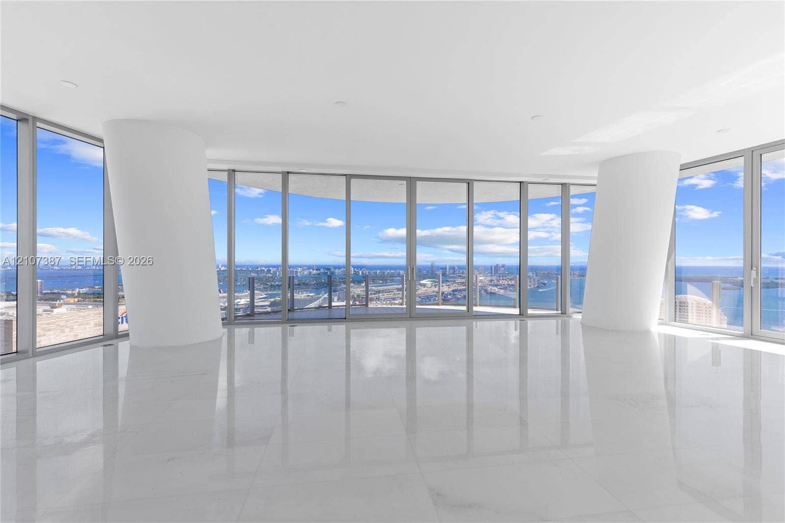 Floor-to-ceiling glass walls, expansive polished stone flooring, structural white columns, and wraparound balcony access