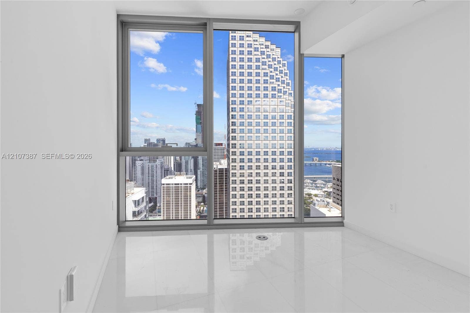 Floor-to-ceiling windows featuring metallic frames, glossy tile flooring, and urban skyscraper backdrop