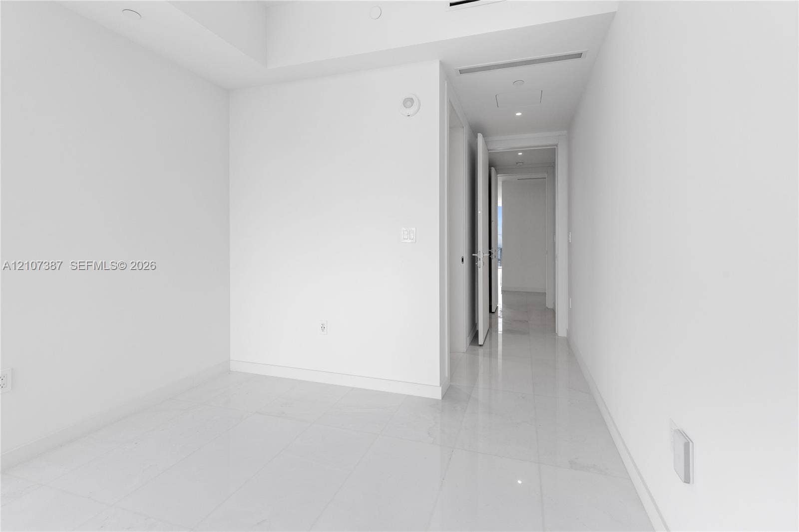 Neutral interior featuring high-gloss tile flooring, recessed ceiling lighting, and smooth-finish walls