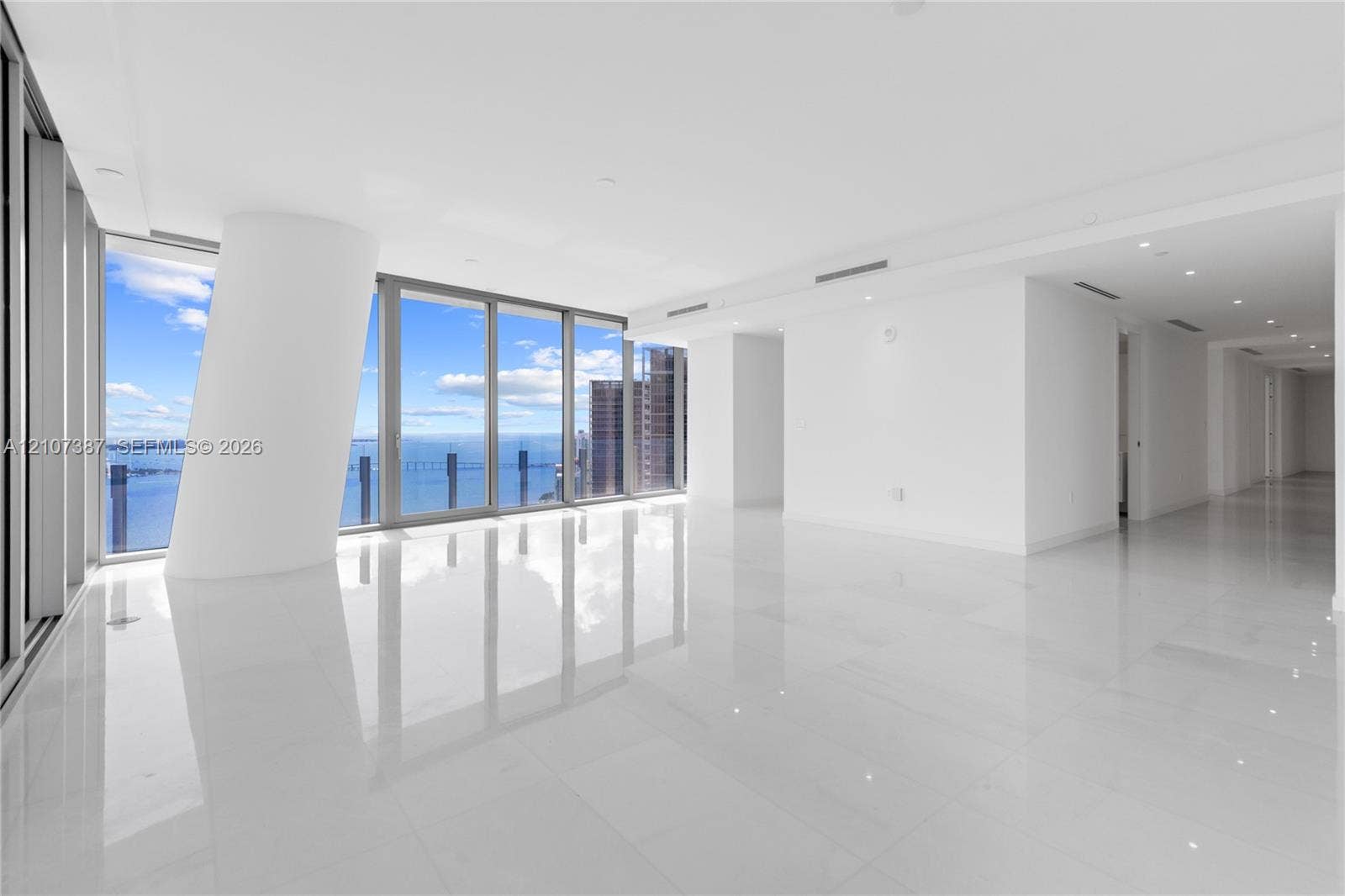 Open-concept interior featuring floor-to-ceiling glass windows, water and skyline scenery, polished tile flooring, and recessed ceiling lighting