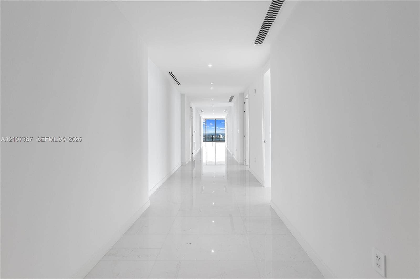 Hallway featuring polished tile flooring, recessed ceiling lighting, and floor-to-ceiling windows