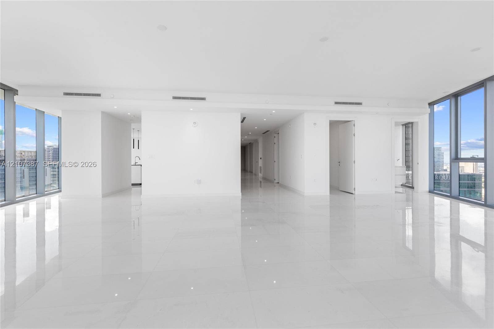 Open-concept interior featuring floor-to-ceiling windows, polished stone-finish flooring, and recessed ceiling lighting