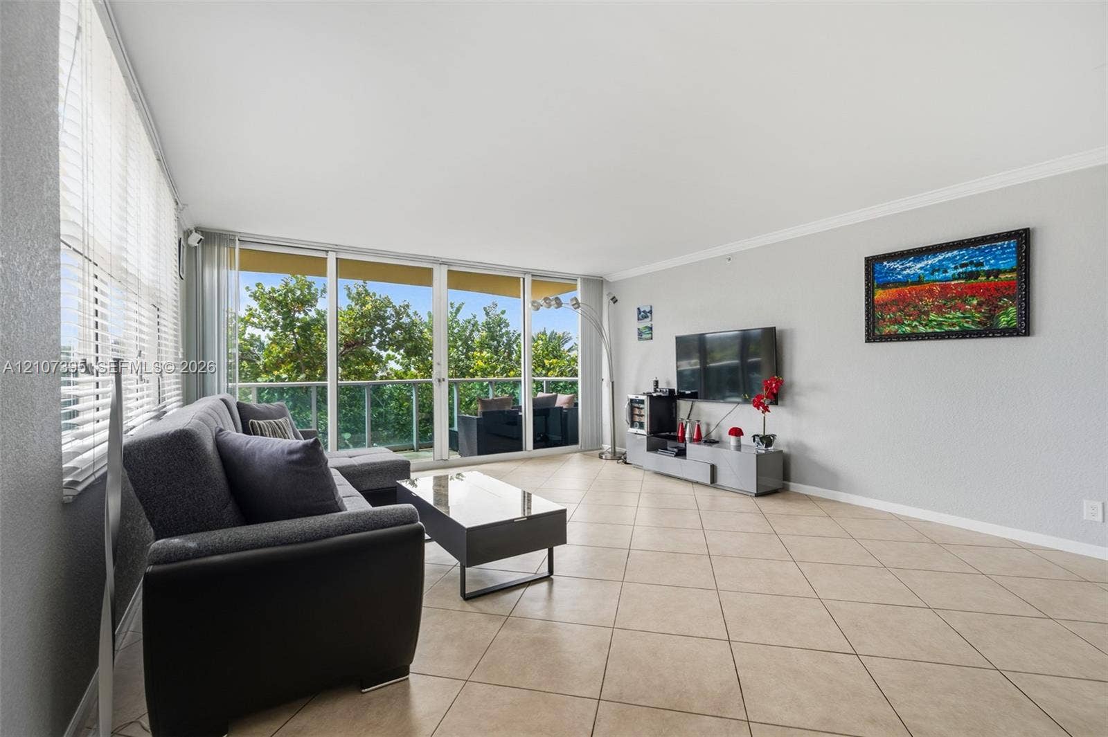 Living space featuring tile flooring, crown molding, and floor-to-ceiling glass sliding doors opening to a balcony