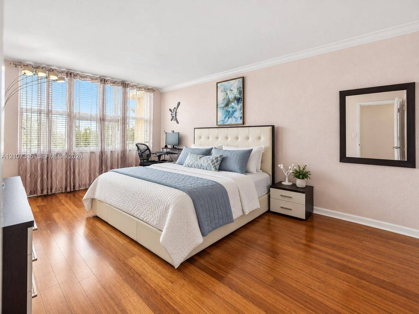 Spacious room featuring wood-finish flooring, crown molding, and an expansive window wall with integrated blinds