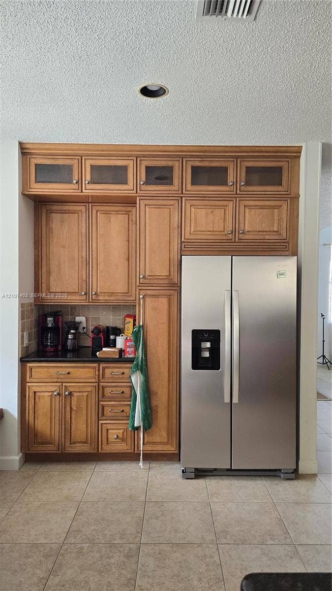 1559 Elm Grove Road, Weston, Weston, FL 33327 Custom built-in cabinetry featuring glass-panel upper doors, integrated stainless steel side-by-side refrigerator, stone-surfaced countertop, and tiled flooring