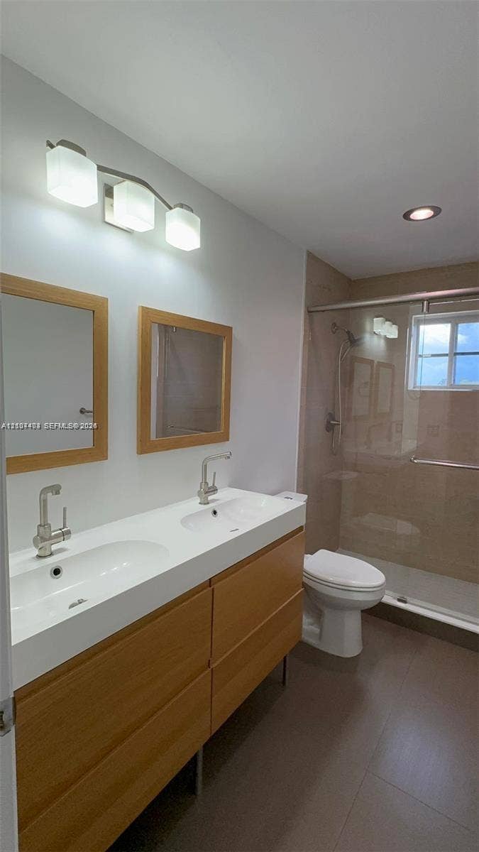 1559 Elm Grove Road, Weston, Weston, FL 33327 Dual-sink vanity with wood-finish cabinetry, rectangular under-mount basins, polished chrome fixtures, two wood-framed mirrors, and a glass-enclosed shower