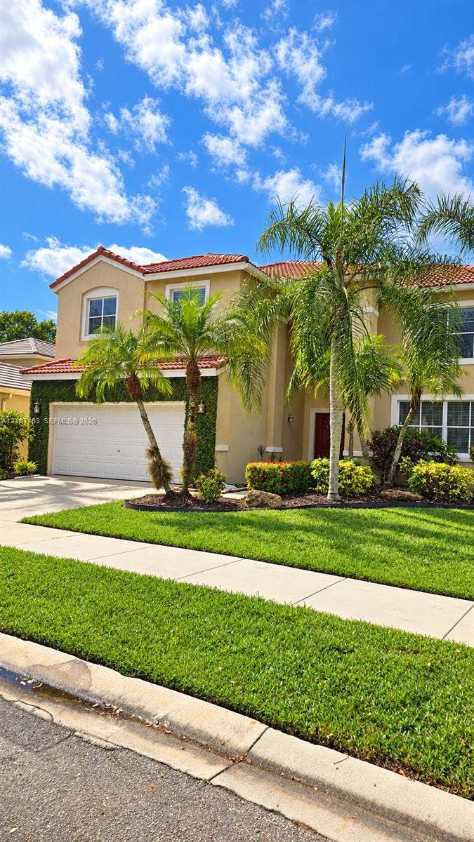1559 Elm Grove Road, Weston, Weston, FL 33327 Two-story residence featuring a terracotta-tiled roof, stucco exterior, multi-pane windows, and a paved driveway leading to an attached two-car garage