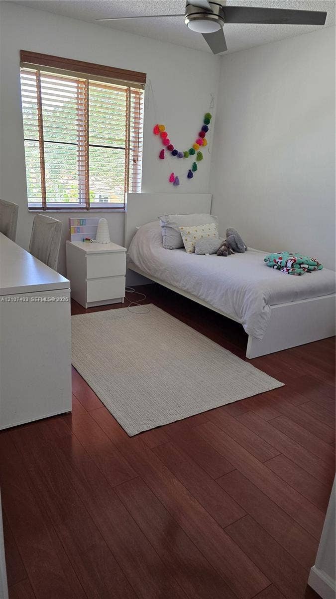 1559 Elm Grove Road, Weston, Weston, FL 33327 Bedroom featuring wood-finish flooring, a neutral color palette, a horizontal window with wood-slat blinds, and a ceiling-mounted light fixture with a fan