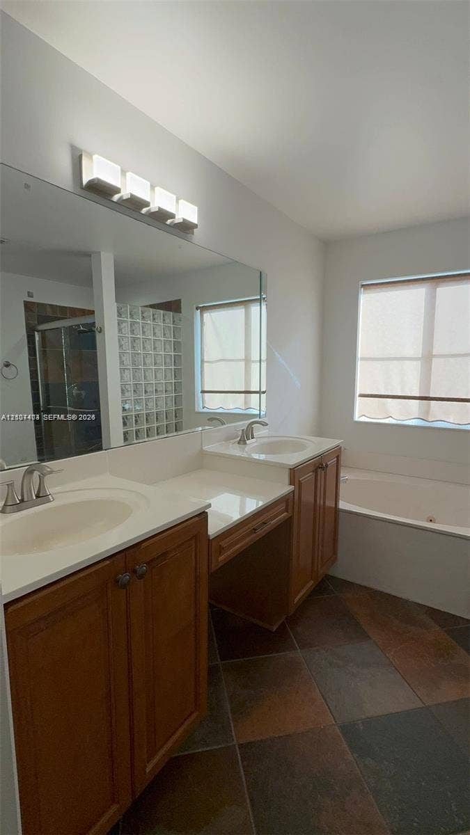 1559 Elm Grove Road, Weston, Weston, FL 33327 Dual-sink vanity with wood-finish cabinetry, solid-surface countertops, expansive wall mirror, and large-format tile flooring