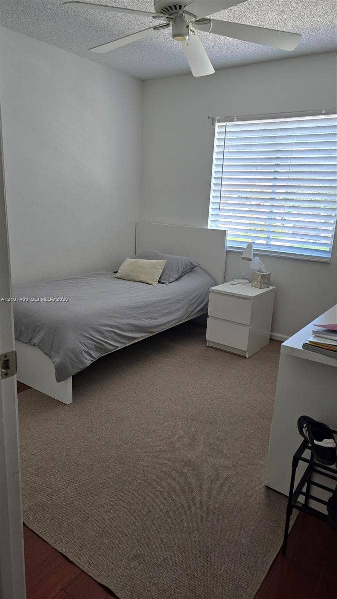 1559 Elm Grove Road, Weston, Weston, FL 33327 Neutral-toned carpeting, ceiling-mounted paddle fan, and large window with horizontal blinds