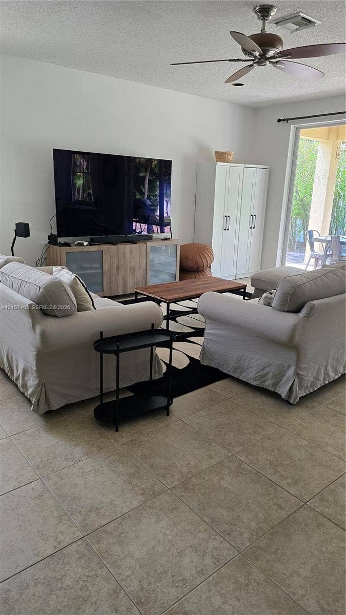 1559 Elm Grove Road, Weston, Weston, FL 33327 Neutral-toned tile flooring, ceiling fan with light fixture, and floor-to-ceiling glass sliding doors