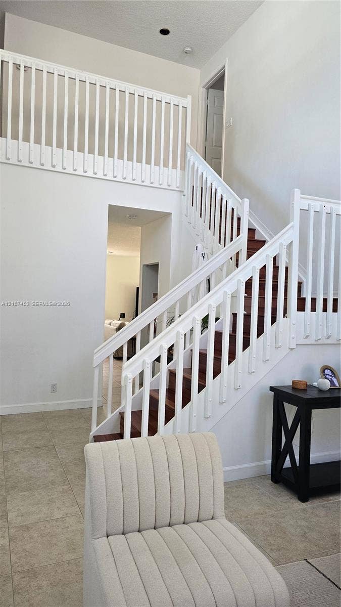 1559 Elm Grove Road, Weston, Weston, FL 33327 High-ceiling foyer featuring a staircase with wood-finish treads, white railings, and tile flooring