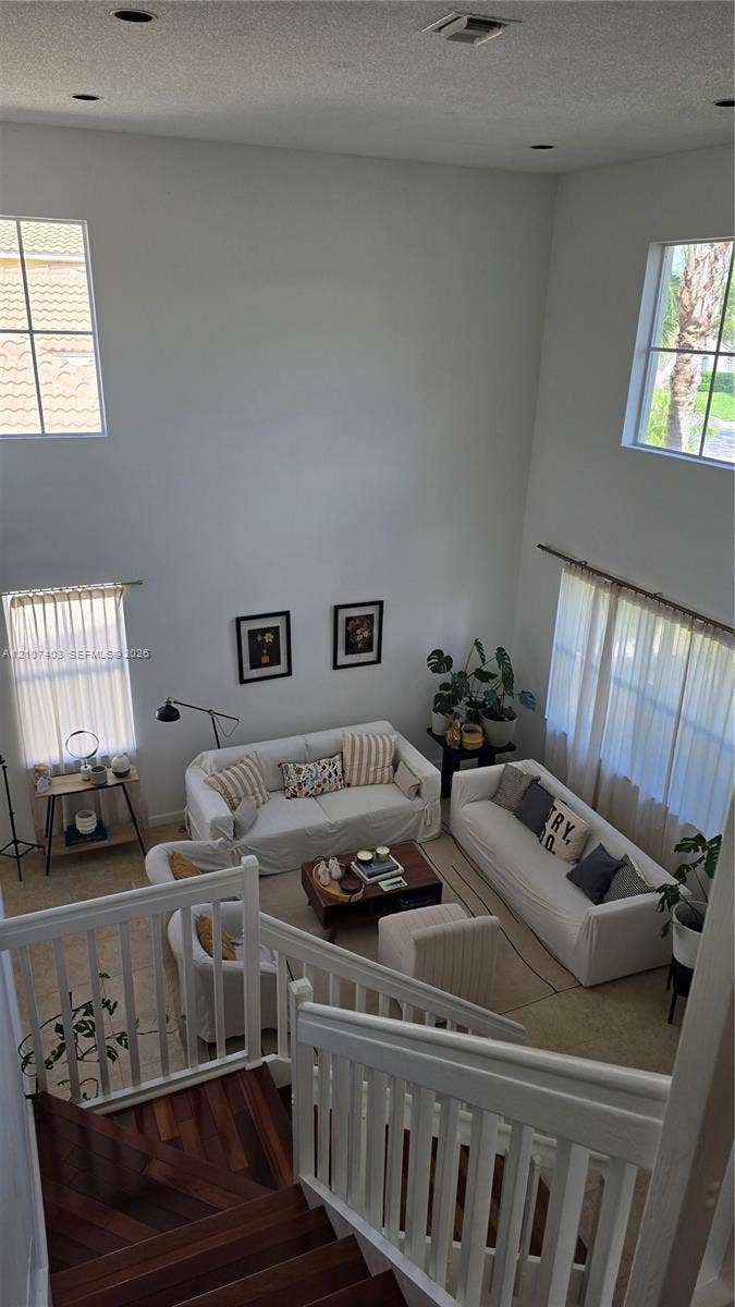 1559 Elm Grove Road, Weston, Weston, FL 33327 High-ceiling living area featuring multi-level windows, wood-finish staircase treads, and white vertical baluster railing