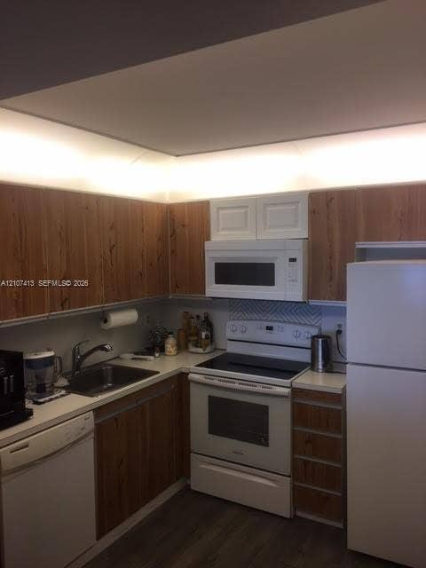 2301 S Ocean Drive, #1606, Hollywood, Hollywood, FL 33019 Kitchen featuring wood-finish cabinetry, white appliances, integrated under-cabinet lighting, a chevron-patterned backsplash, and a single-basin stainless steel sink