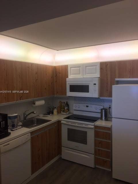 2301 S Ocean Drive, #1606, Hollywood, Hollywood, FL 33019 Kitchen featuring wood-finish cabinetry, white appliances, integrated cove lighting, and chevron-patterned tile backsplash