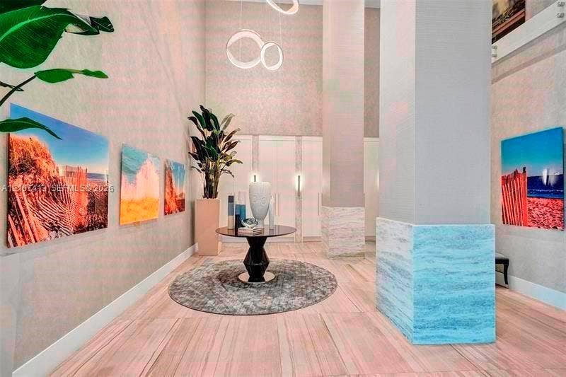 2301 S Ocean Drive, #1606, Hollywood, Hollywood, FL 33019 High-ceiling foyer featuring stone tile flooring, a prominent structural column with stone detailing, minimalist ring pendant lighting, and floor-to-ceiling built-in cabinetry