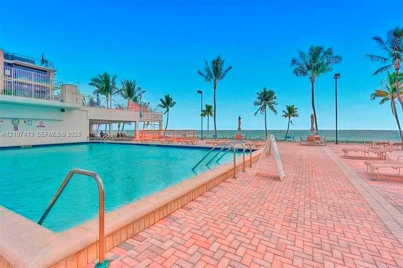 2301 S Ocean Drive, #1606, Hollywood, Hollywood, FL 33019 Oceanfront swimming pool featuring a brick-paver deck, metal ladder entry, and mature palm trees
