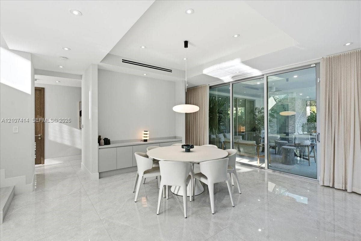 Polished stone-finish flooring, built-in wall cabinetry, recessed ceiling lighting, a modern pendant light fixture, and floor-to-ceiling sliding glass doors