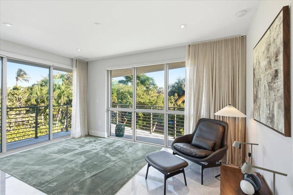 Floor-to-ceiling sliding glass doors, polished stone flooring, recessed lighting, and a metal-railed balcony