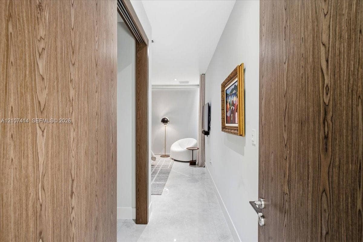 Solid wood-finish doors with brushed nickel lever hardware, polished stone flooring, and recessed ceiling lighting