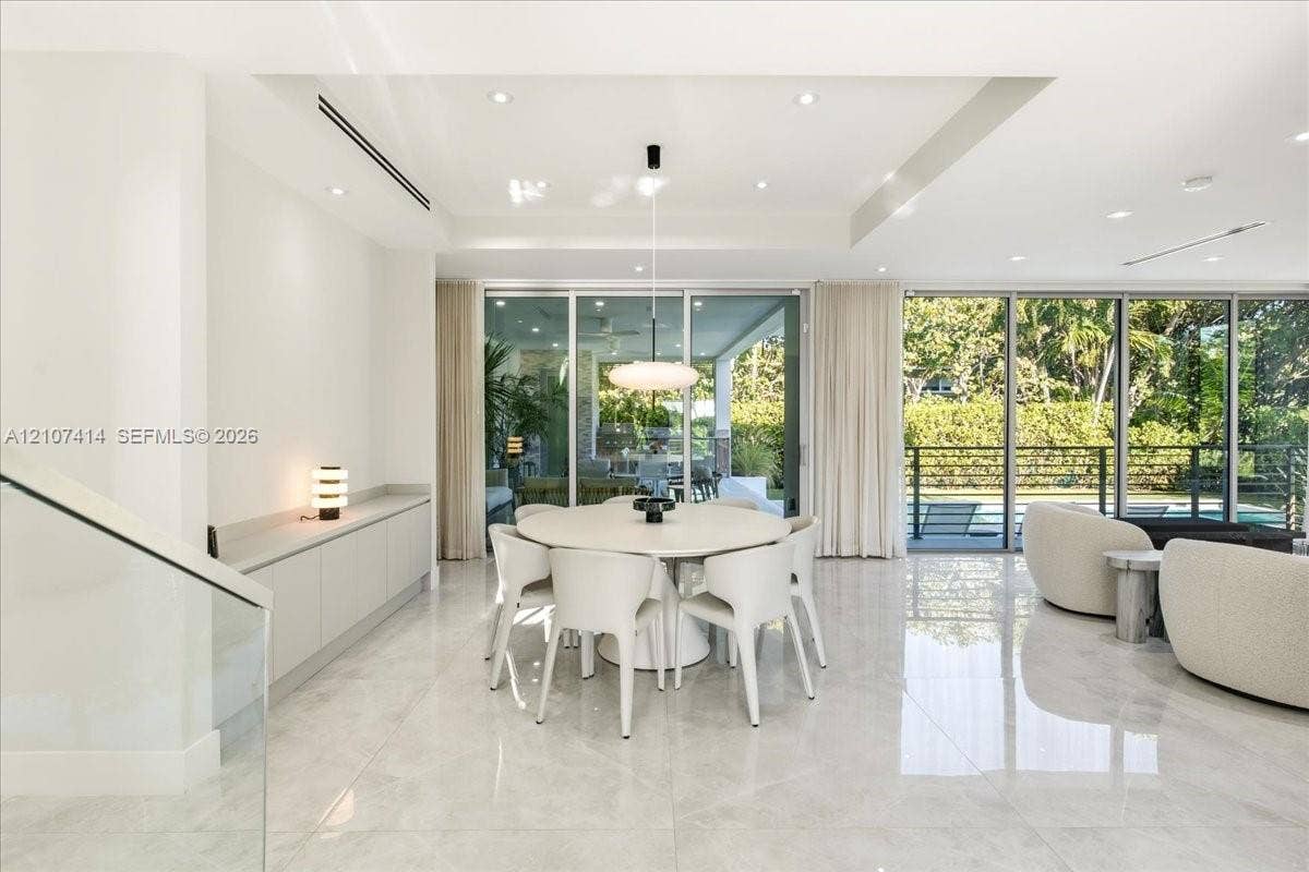 Open-concept interior featuring large-format tile flooring, floor-to-ceiling glass sliding doors, recessed lighting, and custom built-in cabinetry with a stone-top surface