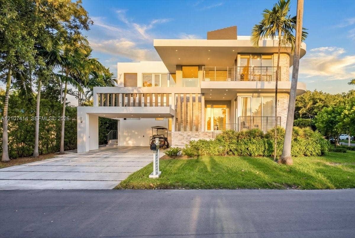 Modern multi-level exterior featuring clean geometric lines, stacked stone facade accents, multiple covered balconies with cable railings, and a wide paved driveway