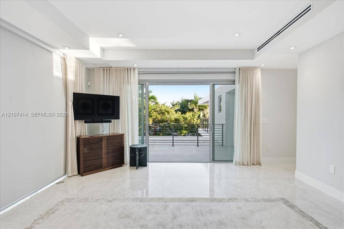 Interior space featuring polished stone flooring, recessed ceiling lighting, a linear HVAC diffuser, and expansive multi-panel sliding glass doors opening to a covered balcony