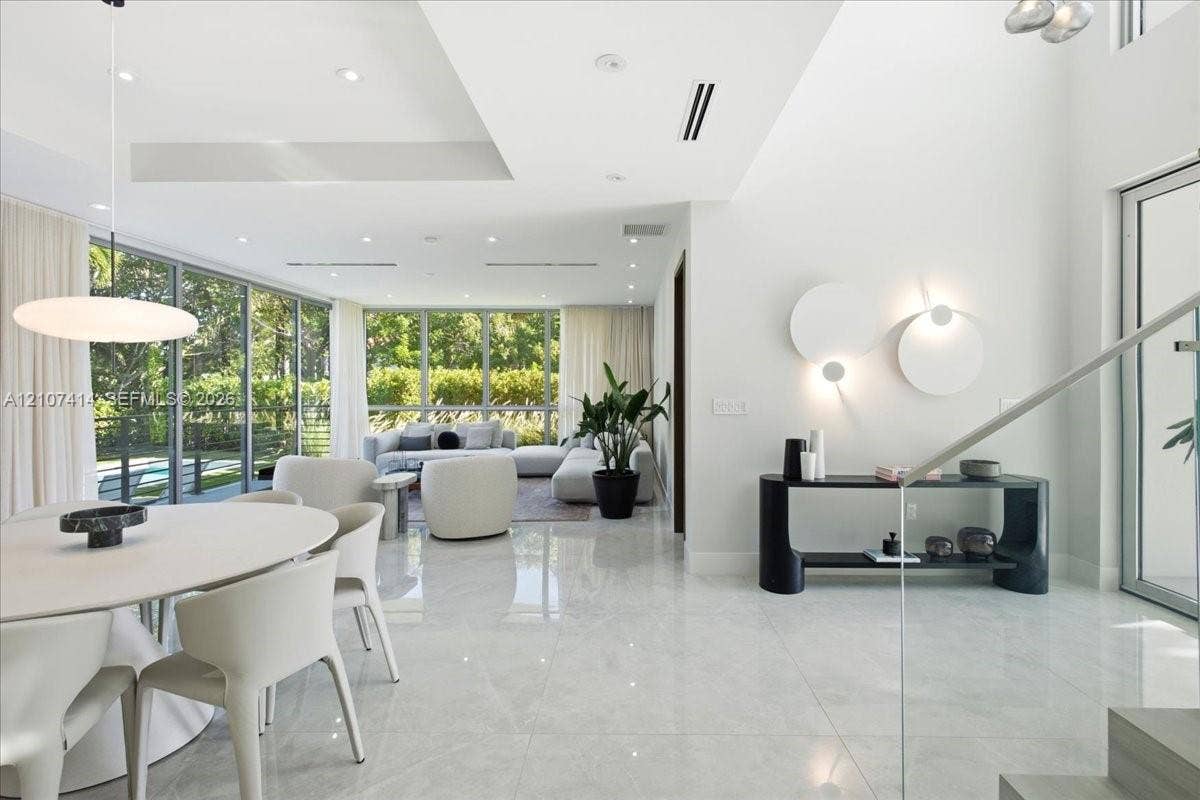 Open-concept interior featuring floor-to-ceiling glass walls, large-format tile flooring, recessed lighting, and sculptural wall-mounted fixtures