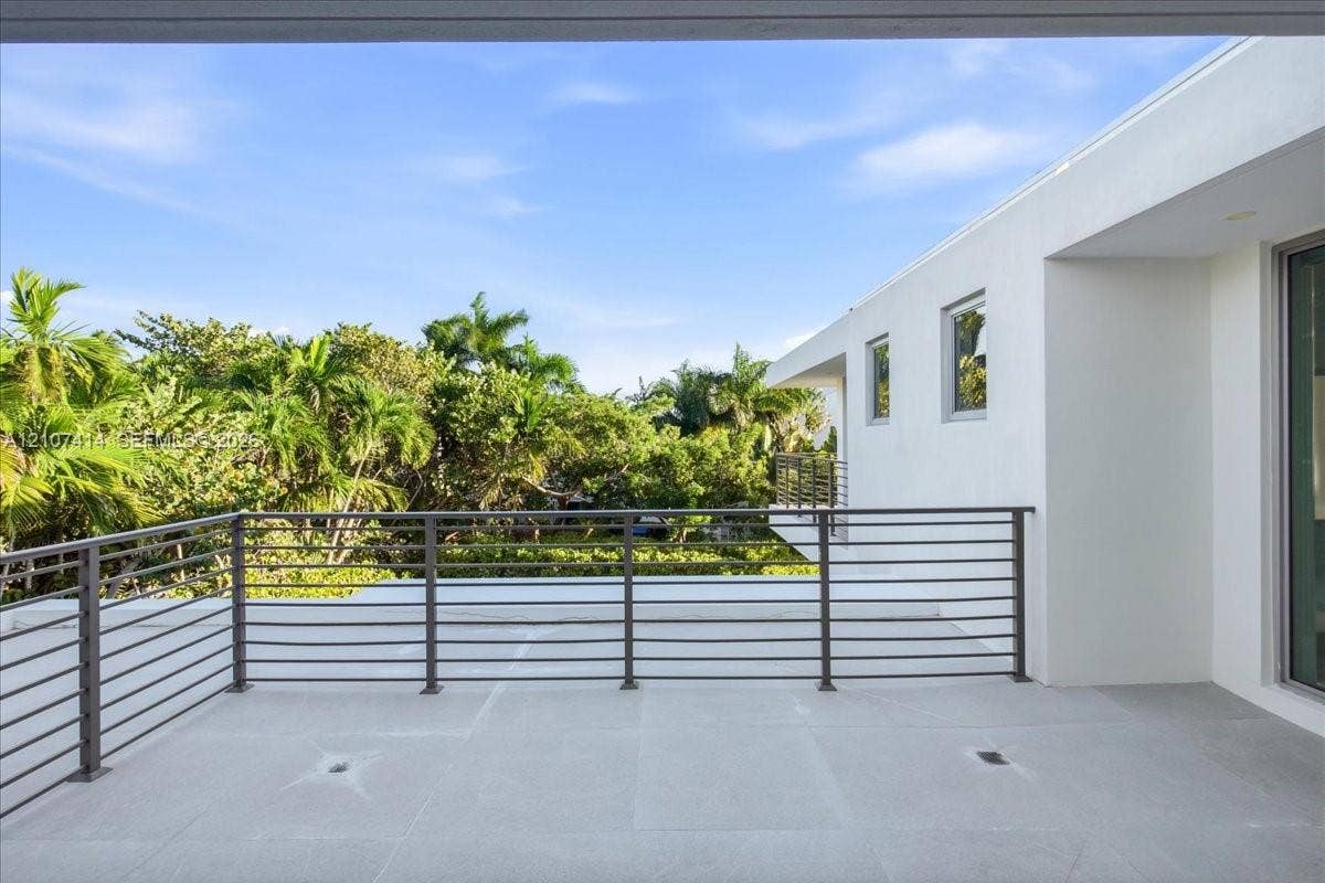 Elevated terrace featuring a smooth concrete floor, horizontal metal railing, and white stucco exterior walls
