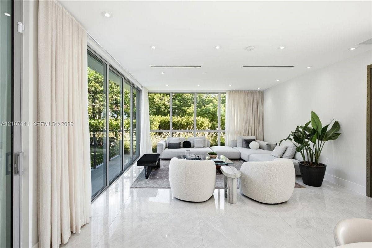Open-concept interior featuring large-format polished stone flooring, floor-to-ceiling glass sliding doors, expansive glass windows, and recessed lighting