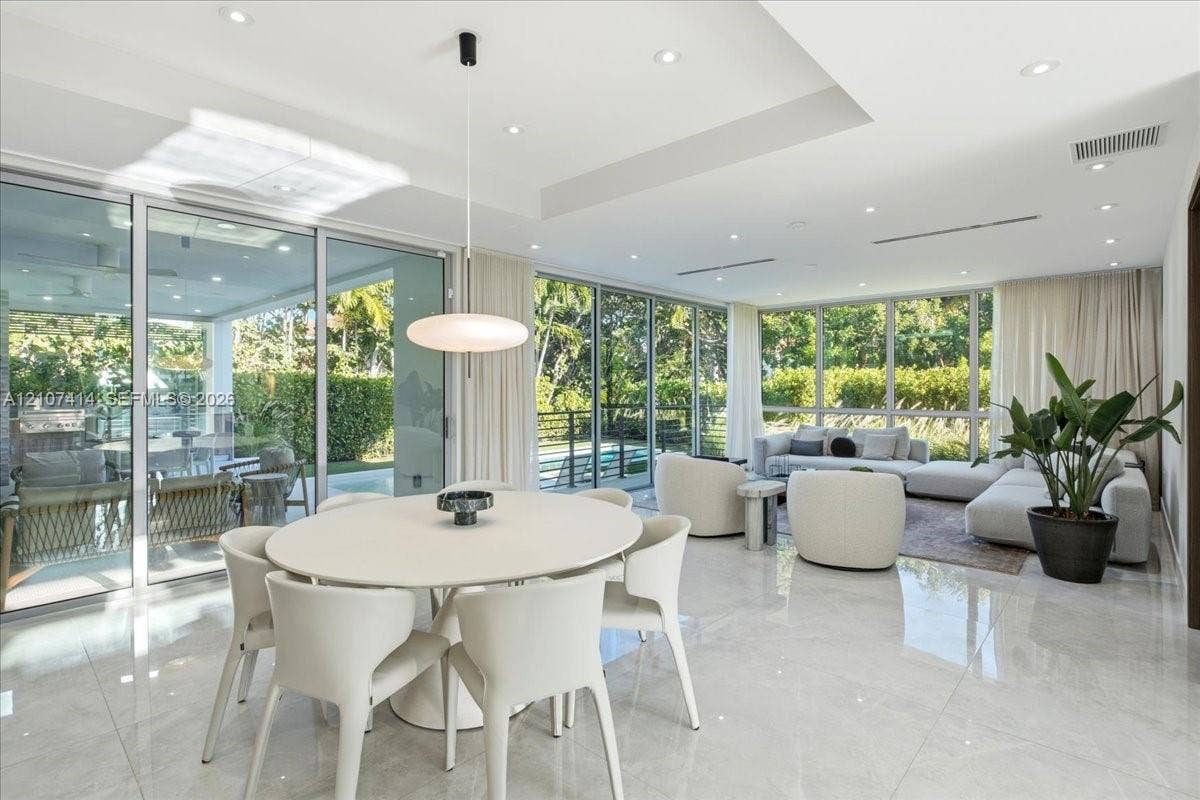 Open-concept interior featuring large-format tile flooring, recessed ceiling lighting, a tray ceiling detail, and floor-to-ceiling glass sliding doors