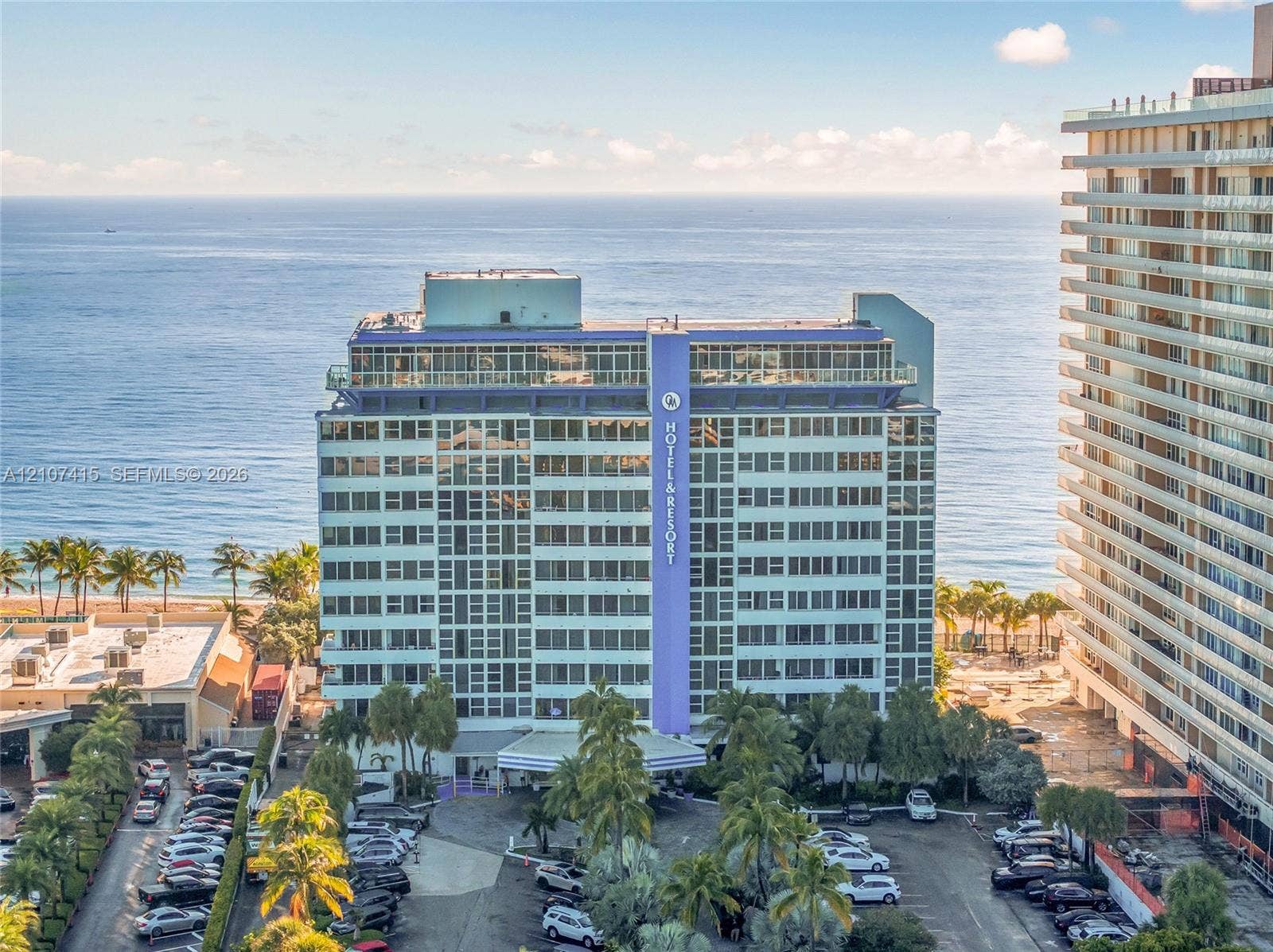 Multi-story residential building featuring a glass-paneled facade, private balconies, and direct oceanfront positioning