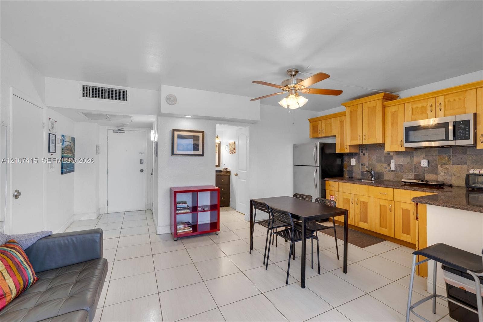 Kitchen featuring light-finish cabinetry, stone tile backsplash, and integrated stainless steel microwave