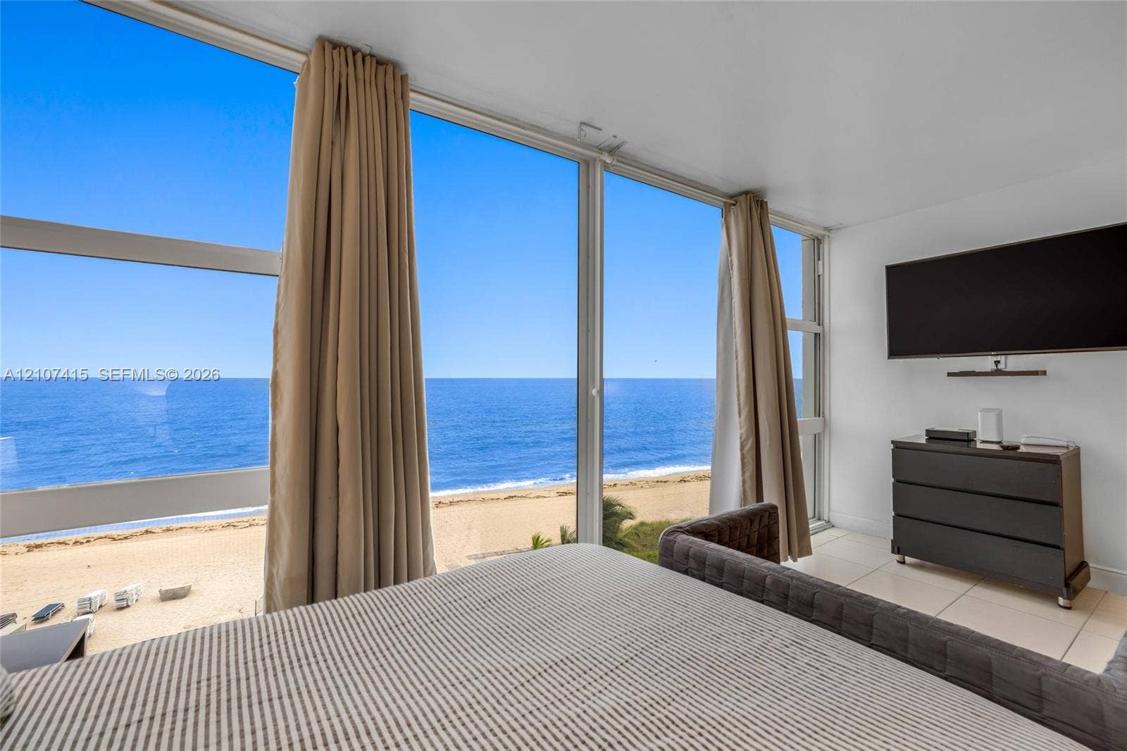 Floor-to-ceiling windows, large-format tile flooring, and coastal scenery