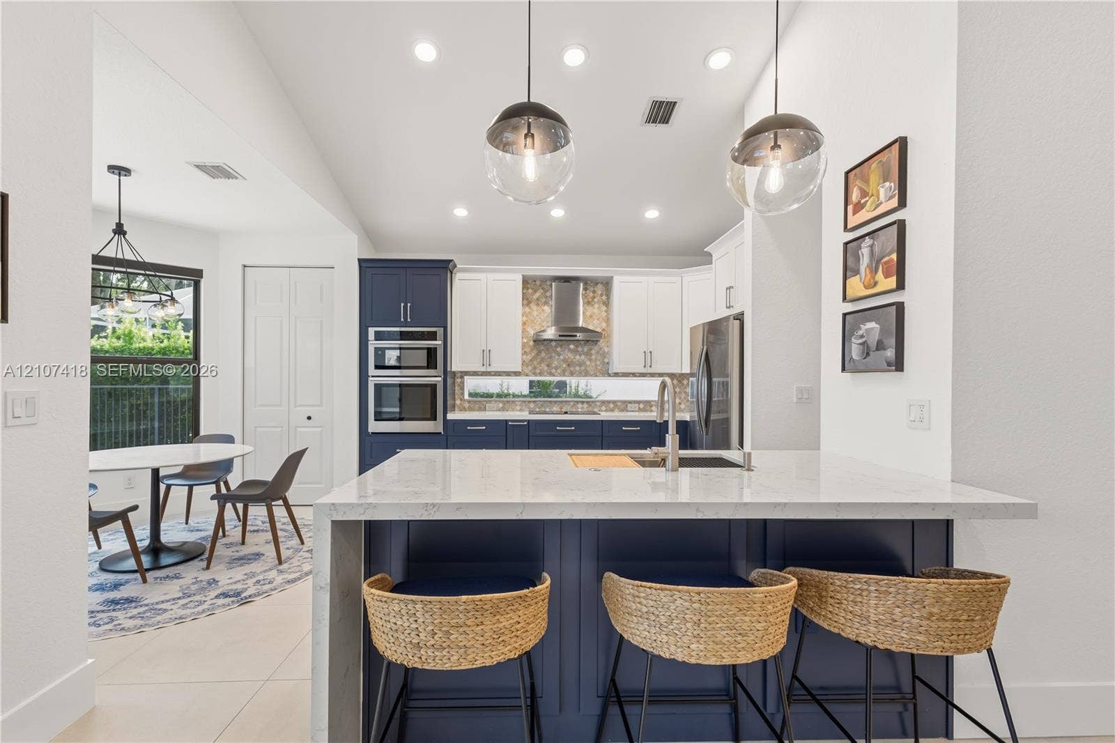 19305 Skyridge Circle, #n/a, Boca Raton, Boca Raton, FL 33498 Kitchen featuring a central island with a solid surface countertop, contrasting navy and white cabinetry, a built-in double wall oven, patterned tile backsplash, and oversized globe pendant lighting