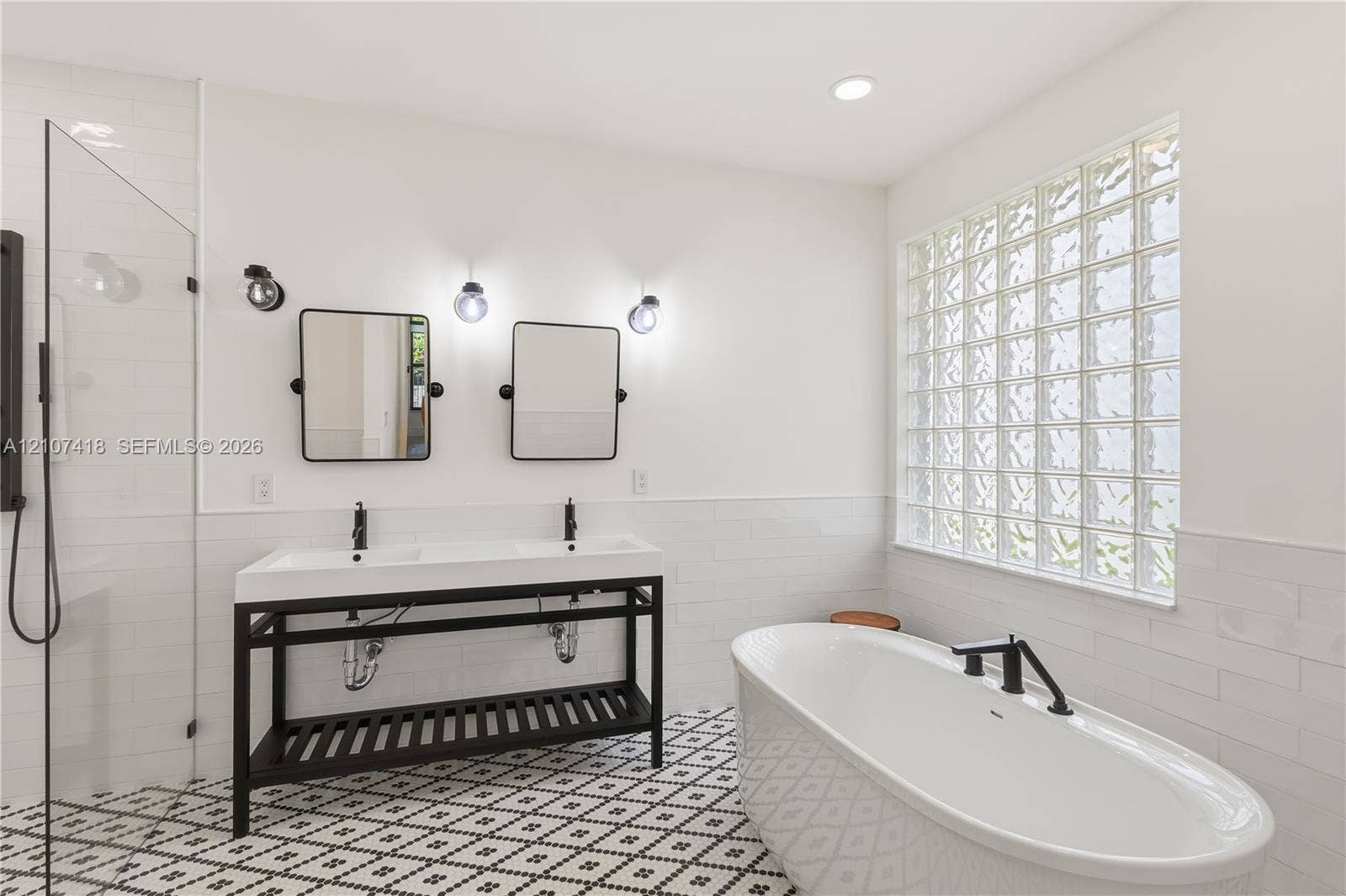 19305 Skyridge Circle, #n/a, Boca Raton, Boca Raton, FL 33498 Double vanity with matte black hardware, freestanding soaking tub, walk-in glass-enclosed shower, patterned floor tile, and glass block window