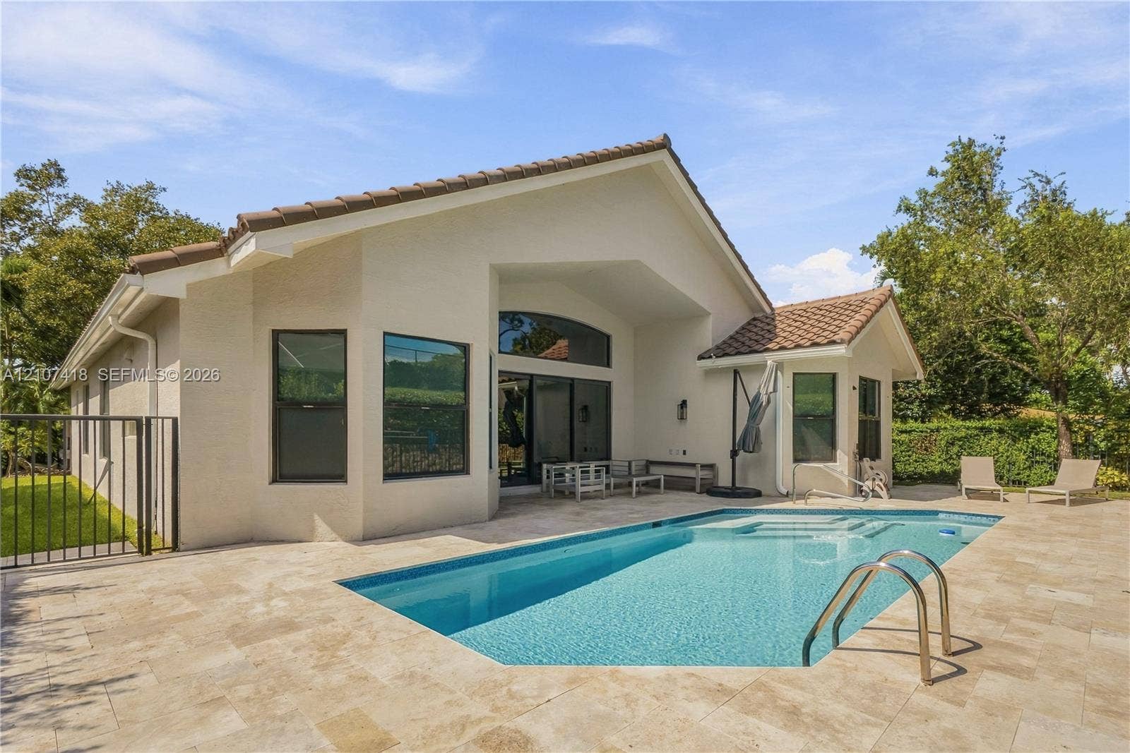 19305 Skyridge Circle, #n/a, Boca Raton, Boca Raton, FL 33498 Rear exterior featuring a tile roof, stucco siding, stone paver decking, and a built-in swimming pool