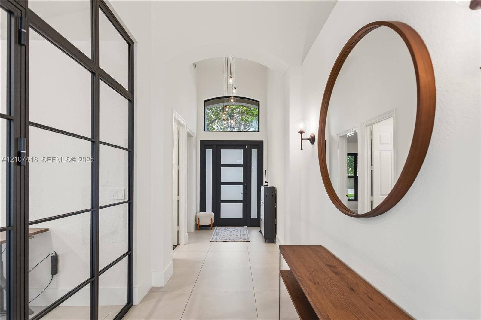 19305 Skyridge Circle, #n/a, Boca Raton, Boca Raton, FL 33498 Entryway featuring large-format tile flooring, a vaulted ceiling with a pendant light, an arched transom window, and a metal-framed glass partition wall