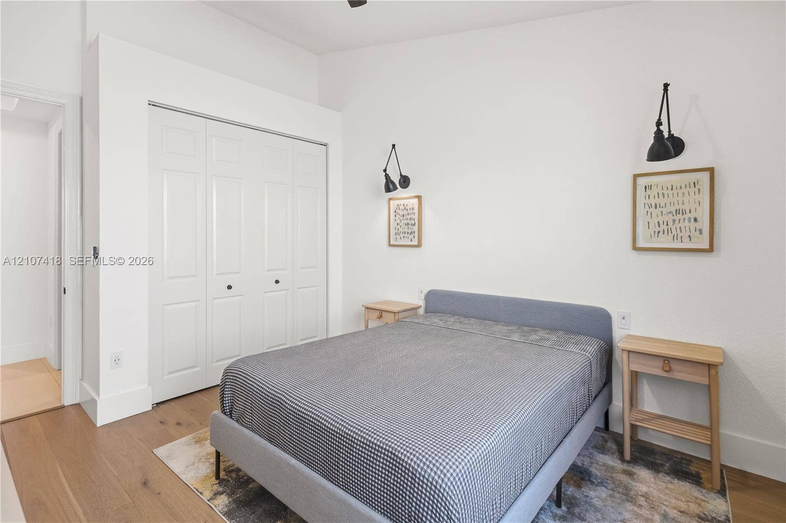 19305 Skyridge Circle, #n/a, Boca Raton, Boca Raton, FL 33498 Room featuring wood-finish flooring, white bi-fold closet doors, and dual black wall-mounted swing-arm sconces