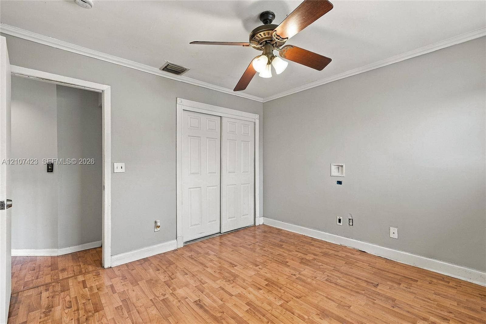 650 NE 195th Street, Miami, FL 33179 Interior space featuring wood-finish flooring, crown molding, a central ceiling fan with integrated lighting, and a double-panel closet door