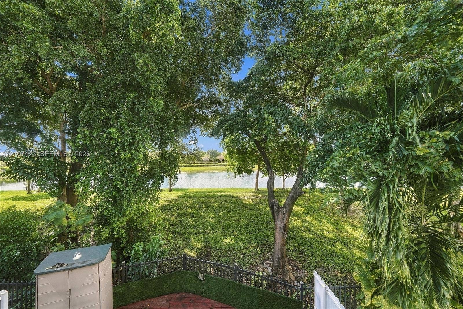 650 NE 195th Street, Miami, FL 33179 Backyard featuring mature trees, a water feature, ground-level hardscaping, and decorative perimeter fencing