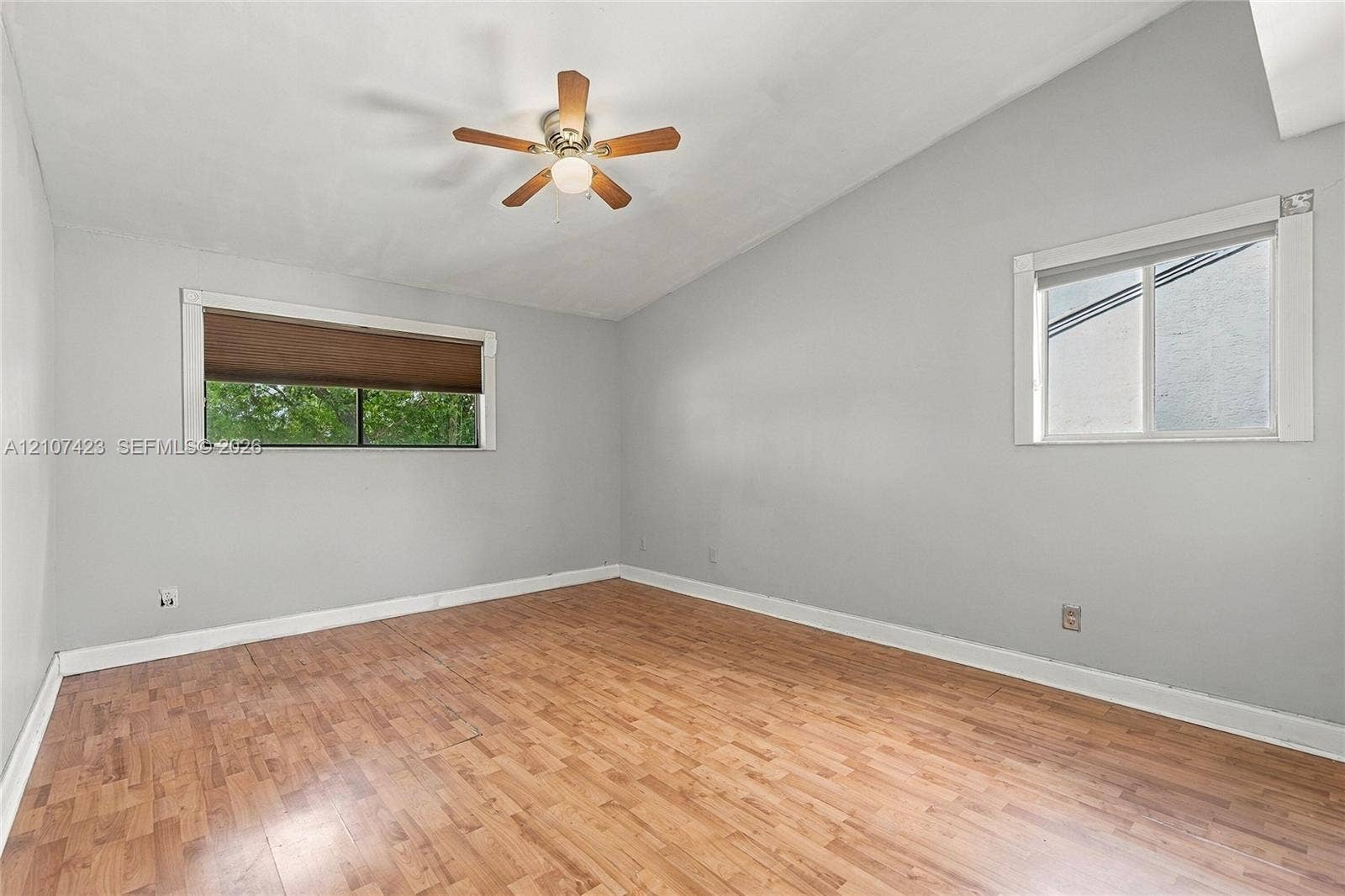 650 NE 195th Street, Miami, FL 33179 Vaulted ceiling featuring a central wood-finish ceiling fan with integrated lighting, wood-finish flooring, and dual windows