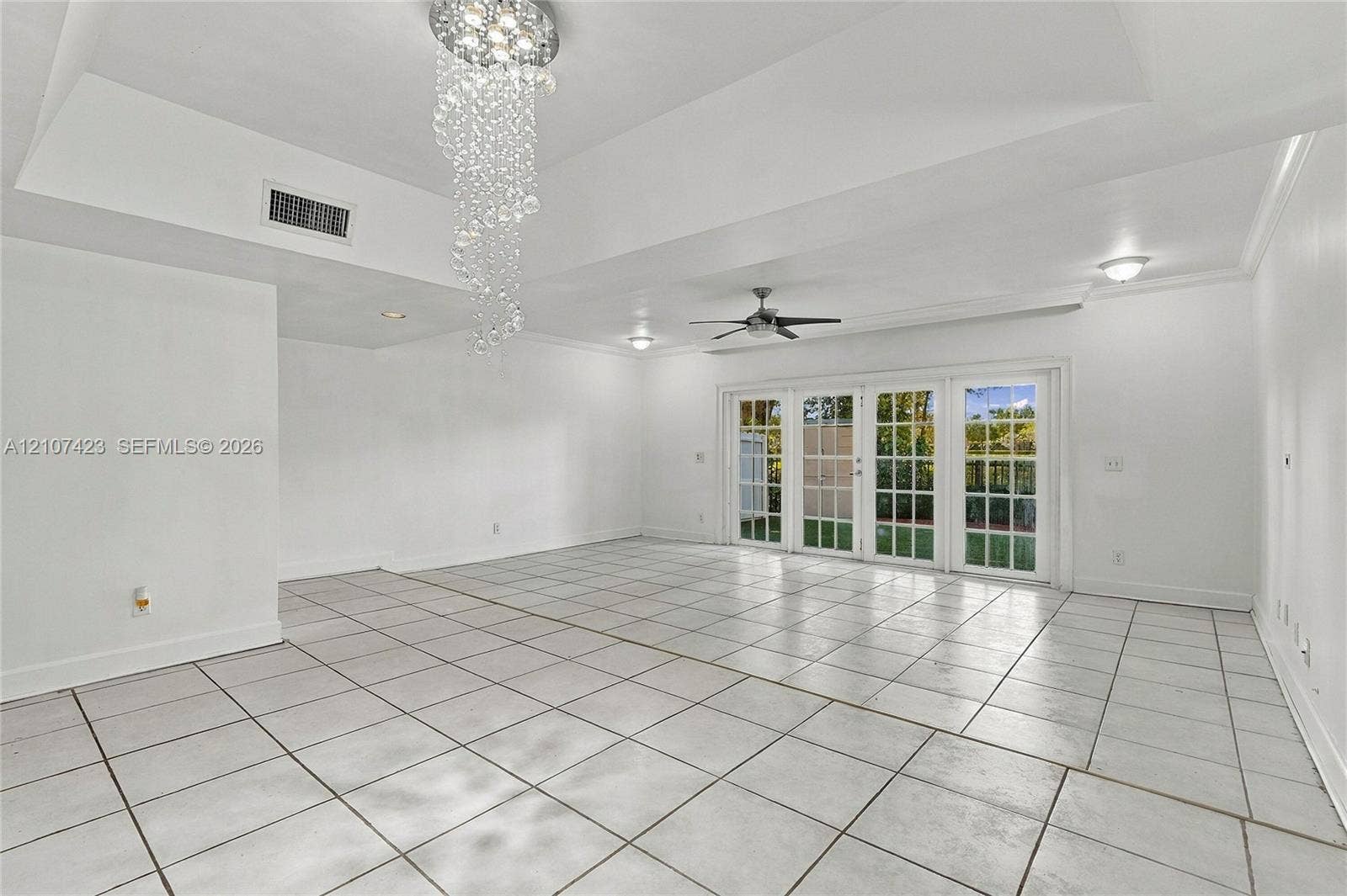 650 NE 195th Street, Miami, FL 33179 Tray ceiling with recessed lighting, crystal-style chandelier, ceramic tile flooring, and multi-panel French doors