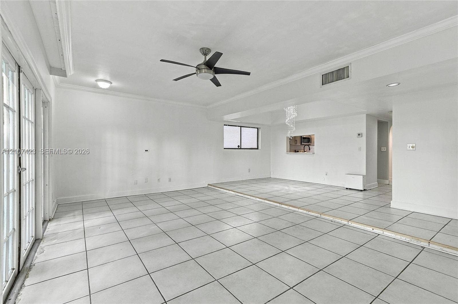 650 NE 195th Street, Miami, FL 33179 Interior space featuring large-format ceramic floor tile, crown molding, a multi-blade ceiling fan with integrated lighting, recessed lighting, and a multi-pane glass door system