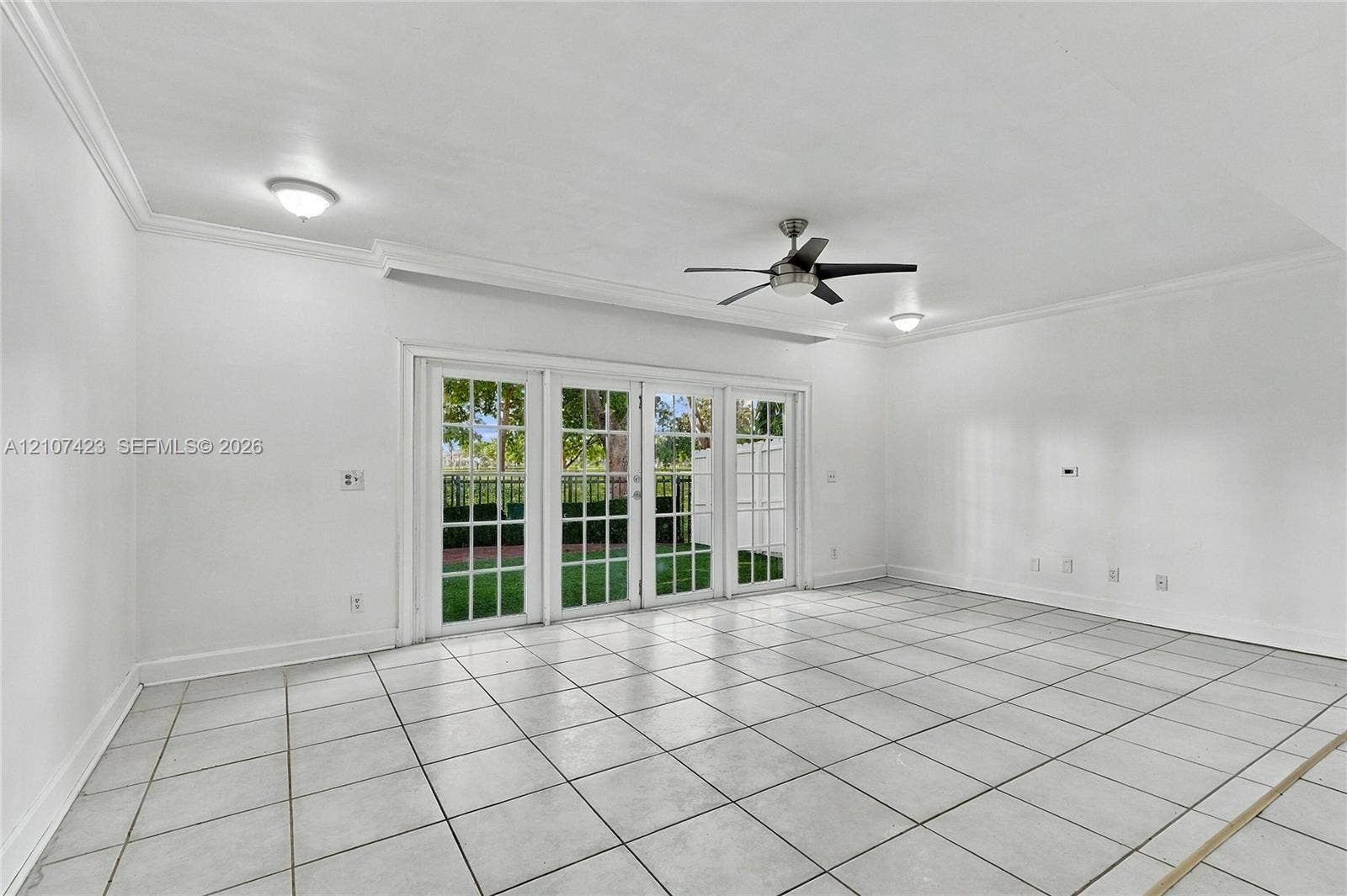 650 NE 195th Street, Miami, FL 33179 Interior space featuring large-format tile flooring, crown molding, multi-panel glass patio doors, and a ceiling fan